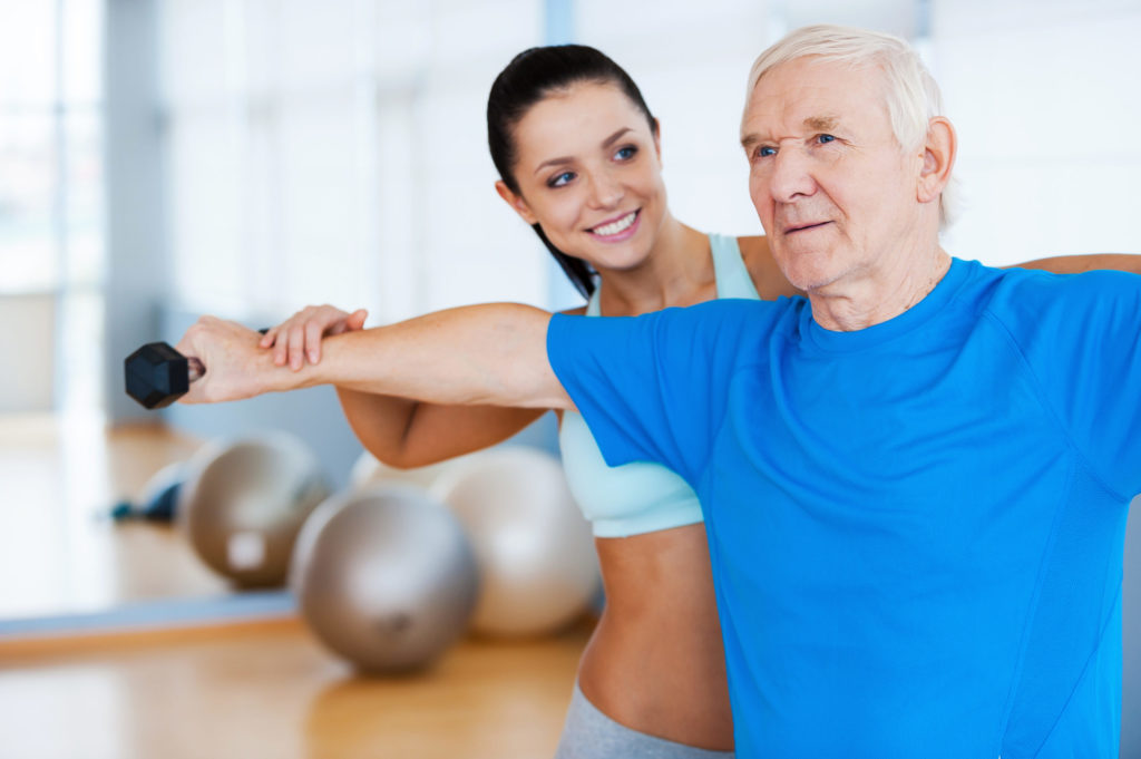 Confident female physical therapist working with senior man in health club