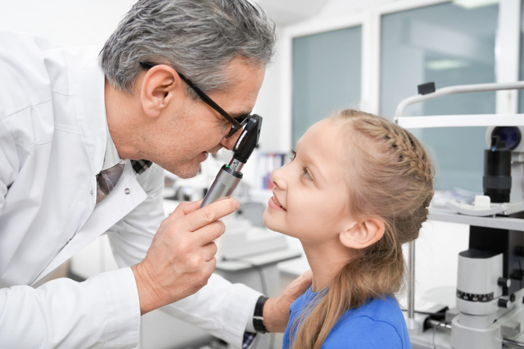 View from side of oculist checking sight of girl in clinic